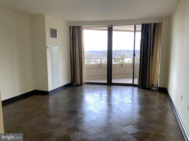 spare room with floor to ceiling windows and dark parquet flooring