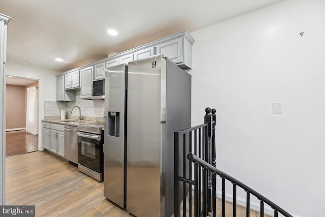 kitchen featuring tasteful backsplash, stainless steel appliances, light hardwood / wood-style floors, and gray cabinetry