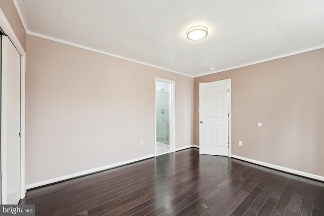 unfurnished bedroom with ensuite bath, dark wood-type flooring, ornamental molding, and a closet