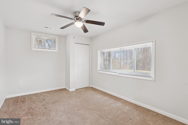 unfurnished bedroom featuring ceiling fan, a closet, and light carpet