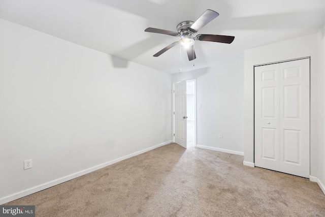 unfurnished bedroom featuring light carpet, a closet, and ceiling fan