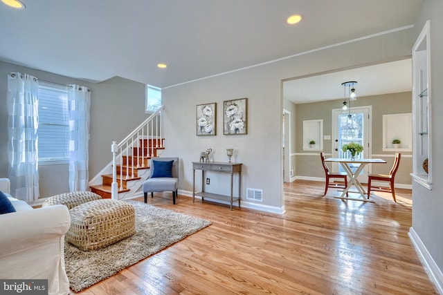 living room featuring crown molding and light hardwood / wood-style flooring