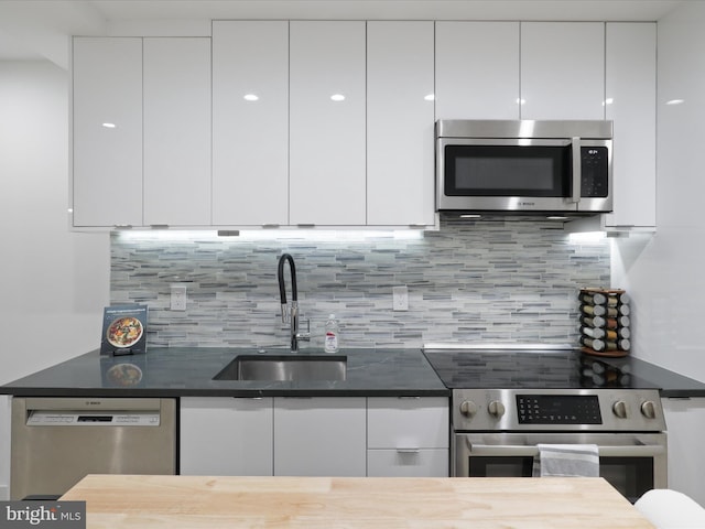 kitchen with stainless steel appliances, white cabinetry, sink, and backsplash