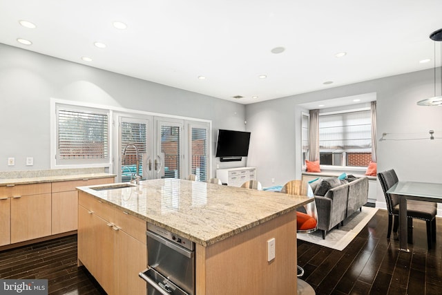 kitchen featuring sink, dark wood-type flooring, a kitchen island with sink, light stone counters, and light brown cabinetry