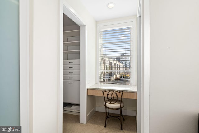 office space with built in desk and light colored carpet