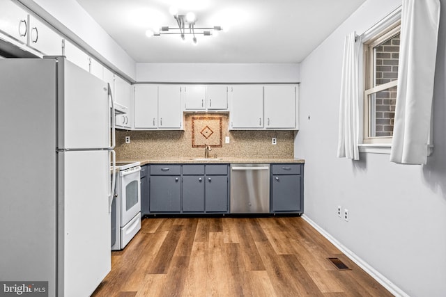 kitchen featuring sink, white appliances, gray cabinets, dark wood-type flooring, and tasteful backsplash