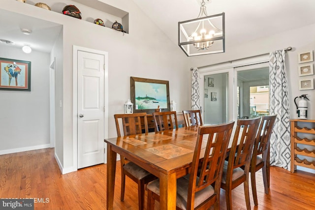 dining room with lofted ceiling, light hardwood / wood-style floors, and a chandelier