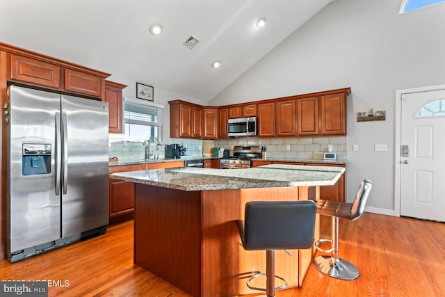 kitchen with stainless steel appliances, tasteful backsplash, a center island, and high vaulted ceiling