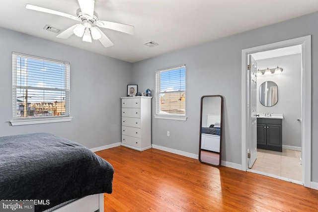 bedroom with light wood-type flooring, ceiling fan, and ensuite bath