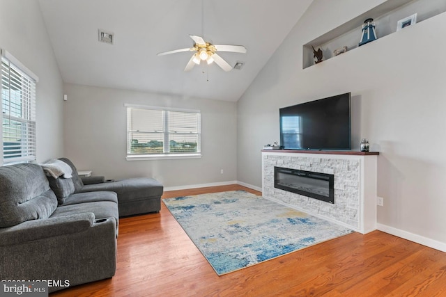 living room featuring hardwood / wood-style floors, vaulted ceiling, a fireplace, and ceiling fan