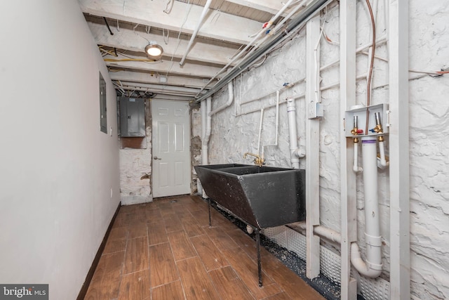 basement with sink, electric panel, and hardwood / wood-style floors