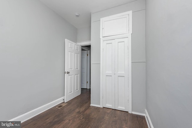 unfurnished bedroom with dark hardwood / wood-style floors and a closet