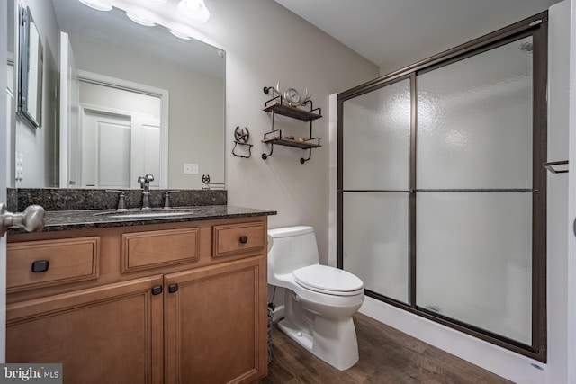 bathroom with vanity, toilet, a shower with shower door, and wood-type flooring