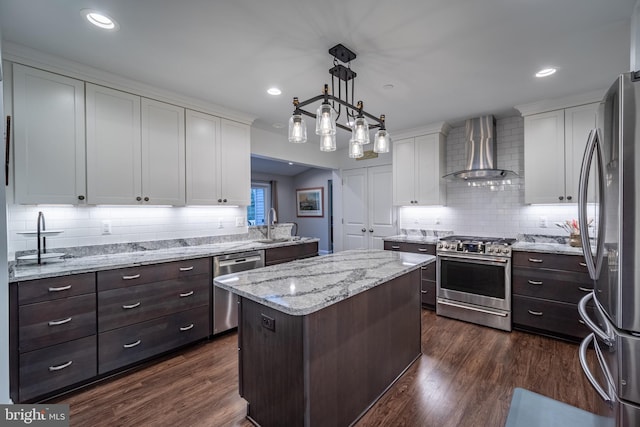 kitchen with sink, hanging light fixtures, a center island, stainless steel appliances, and wall chimney range hood