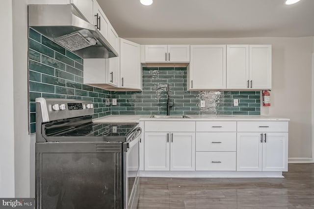 kitchen with sink, electric range, white cabinets, hardwood / wood-style flooring, and backsplash