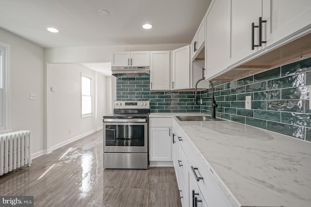 kitchen with radiator heating unit, sink, white cabinets, decorative backsplash, and electric range