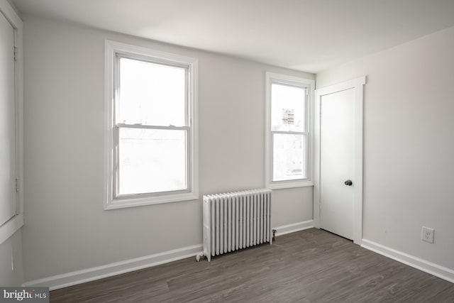 spare room with dark hardwood / wood-style flooring and radiator heating unit