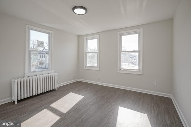 unfurnished room featuring radiator heating unit and dark hardwood / wood-style floors