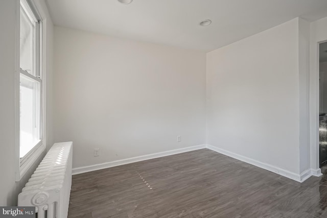 empty room featuring dark hardwood / wood-style floors and radiator heating unit