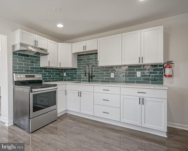 kitchen with electric stove, sink, light hardwood / wood-style flooring, white cabinetry, and backsplash