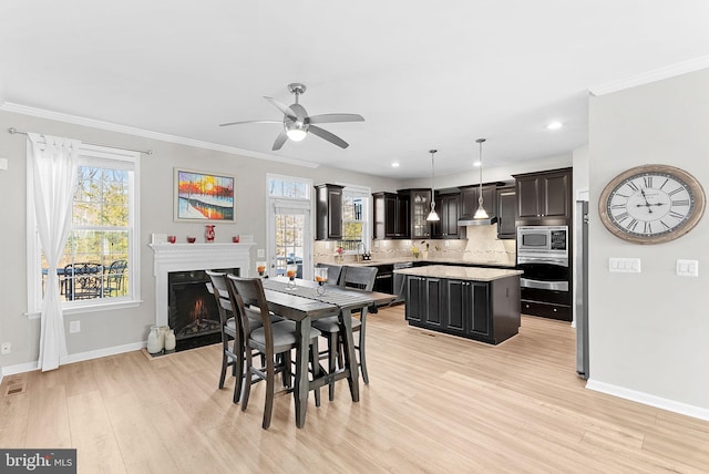 dining room with light wood-type flooring, ornamental molding, and ceiling fan