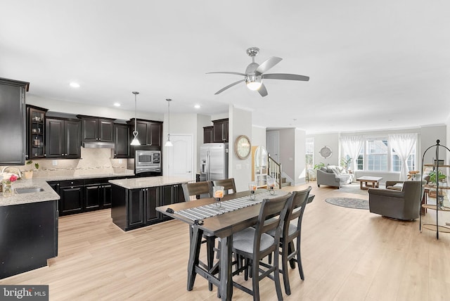 dining room featuring ceiling fan, sink, and light hardwood / wood-style floors