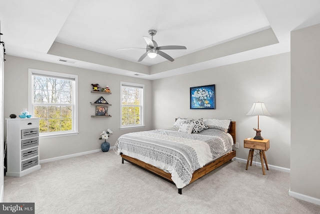 carpeted bedroom featuring a tray ceiling and ceiling fan