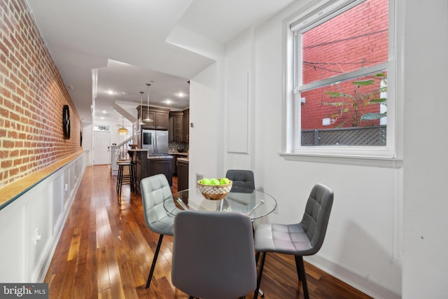 dining room with dark hardwood / wood-style flooring and brick wall