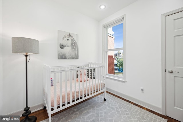 bedroom featuring hardwood / wood-style floors and a nursery area