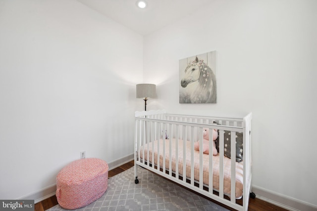 bedroom featuring hardwood / wood-style flooring and a crib