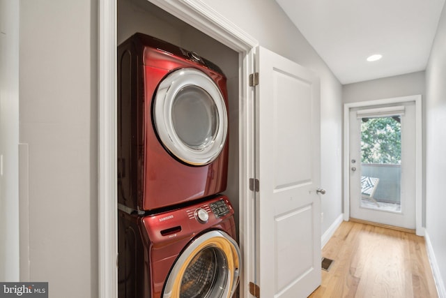 clothes washing area featuring stacked washer / drying machine and light hardwood / wood-style floors