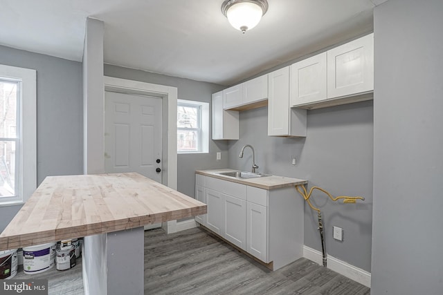 kitchen with sink, white cabinetry, a kitchen breakfast bar, light hardwood / wood-style floors, and wood counters