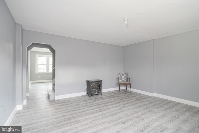 spare room featuring a wood stove and light wood-type flooring