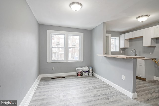 kitchen with white cabinetry, sink, and light hardwood / wood-style floors