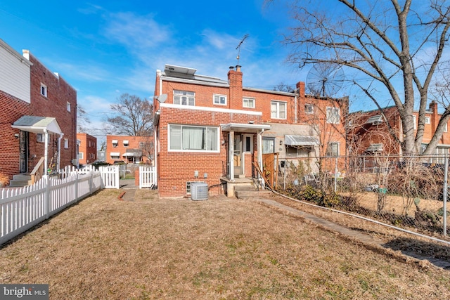 rear view of property featuring central AC unit and a lawn