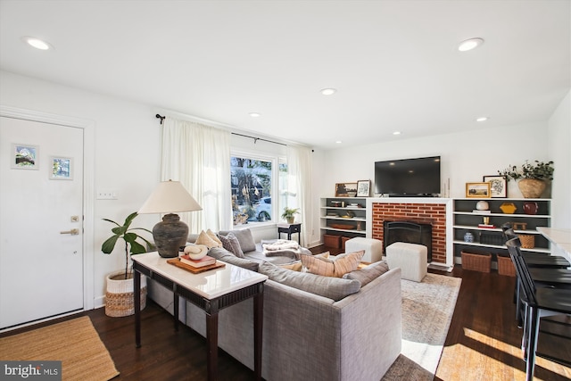 living room featuring a brick fireplace and dark wood-type flooring