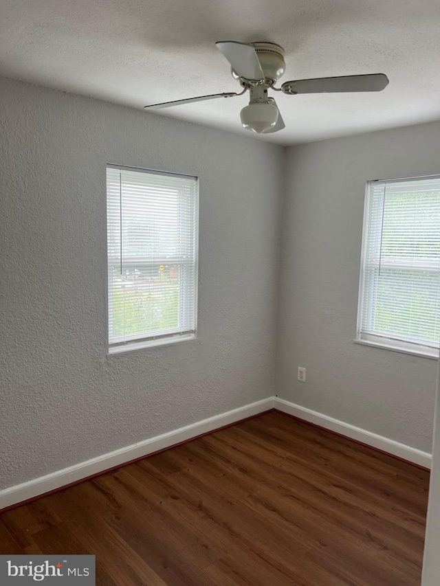 empty room featuring dark wood-type flooring and ceiling fan