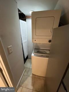 laundry room with light tile patterned flooring and stacked washer and dryer