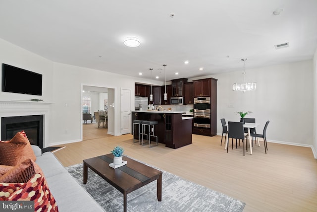 living room with light hardwood / wood-style flooring and a notable chandelier