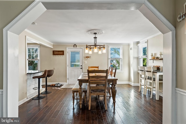 dining space with ornamental molding, a chandelier, and dark hardwood / wood-style flooring