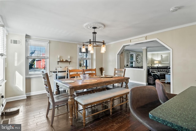 dining space with an inviting chandelier, crown molding, and dark wood-type flooring