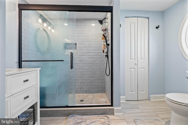 bathroom with vanity, toilet, and a shower with door