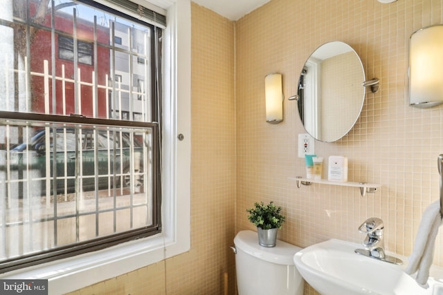 bathroom with tasteful backsplash, sink, tile walls, and toilet