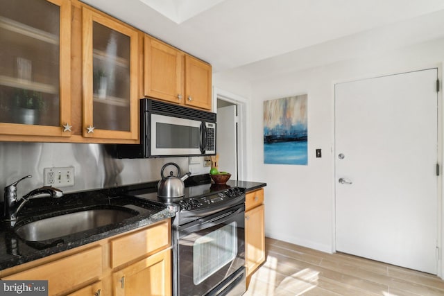 kitchen featuring sink, light hardwood / wood-style floors, black range with electric cooktop, and dark stone countertops