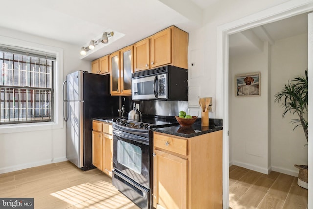 kitchen featuring dark stone counters, light hardwood / wood-style floors, and black appliances