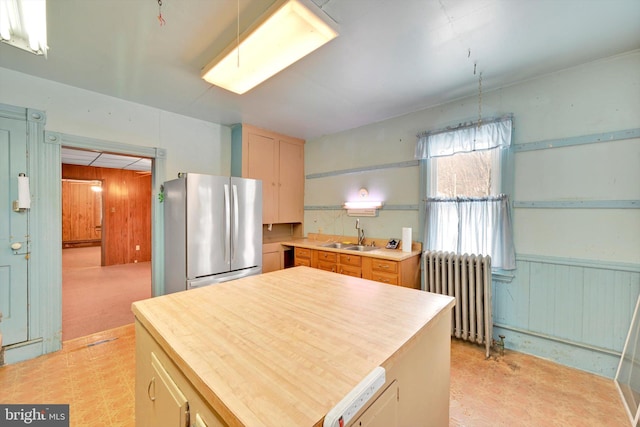 kitchen with sink, stainless steel fridge, radiator heating unit, a center island, and light brown cabinetry