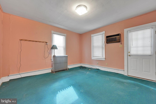 unfurnished room with radiator heating unit, carpet flooring, and a wall mounted air conditioner