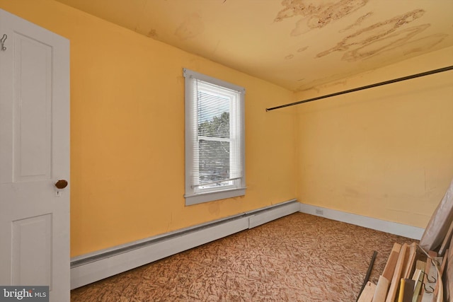 carpeted empty room with a baseboard heating unit