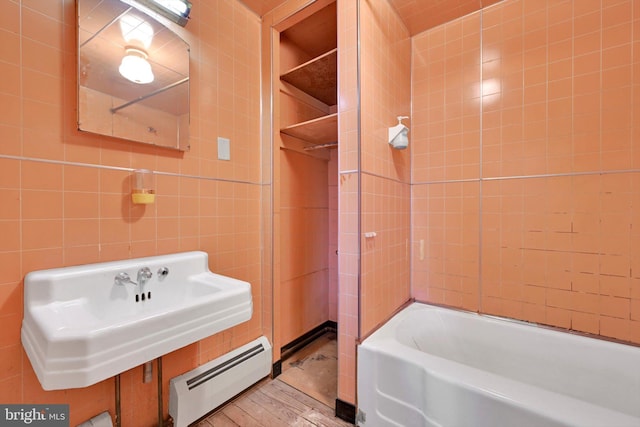 bathroom with a baseboard radiator, tub / shower combination, wood-type flooring, and tile walls