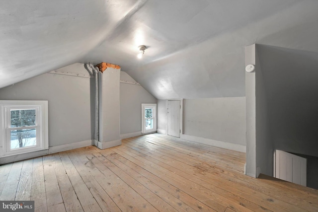 additional living space featuring vaulted ceiling and light wood-type flooring